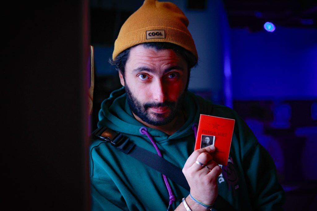 Bodarskyy hält einen roten Ausweis und ein kleines Schwarz-Weiß-Passfoto in die Kamera und schaut ernst